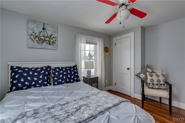 bedroom with ceiling fan, wood finished floors, and baseboards