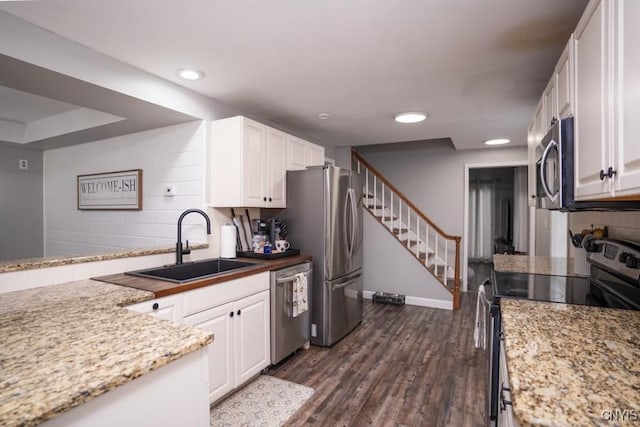 kitchen with tasteful backsplash, appliances with stainless steel finishes, dark wood-style flooring, white cabinetry, and a sink