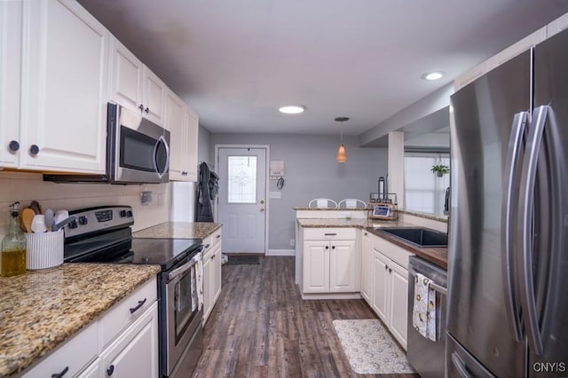 kitchen featuring pendant lighting, stainless steel appliances, tasteful backsplash, dark wood-type flooring, and white cabinetry