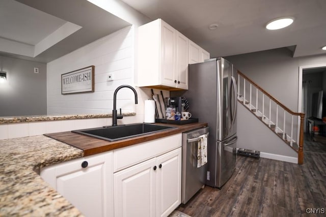 kitchen with dark wood-style floors, a sink, stainless steel appliances, white cabinetry, and backsplash