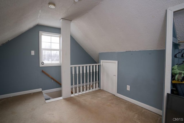 additional living space featuring a textured ceiling, vaulted ceiling, carpet flooring, and baseboards