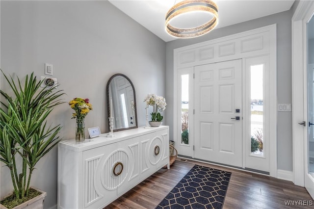 foyer with baseboards, vaulted ceiling, and dark wood-type flooring