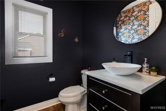 bathroom with toilet, wood finished floors, vanity, and baseboards