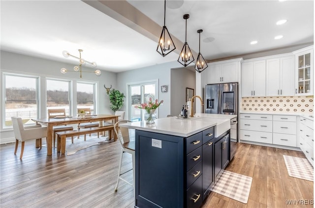 kitchen featuring light wood-style flooring, white cabinets, light countertops, tasteful backsplash, and stainless steel fridge