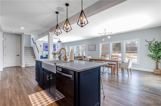 kitchen featuring dark wood-style floors, light countertops, hanging light fixtures, a sink, and dishwasher