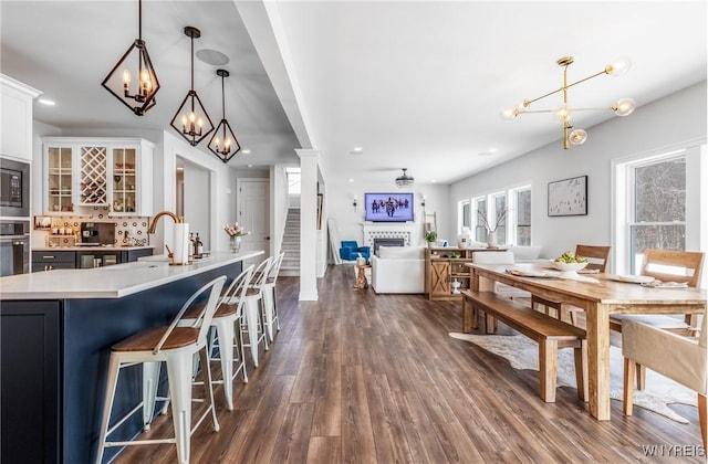 dining room featuring dark wood-style flooring, a fireplace, recessed lighting, an inviting chandelier, and stairs