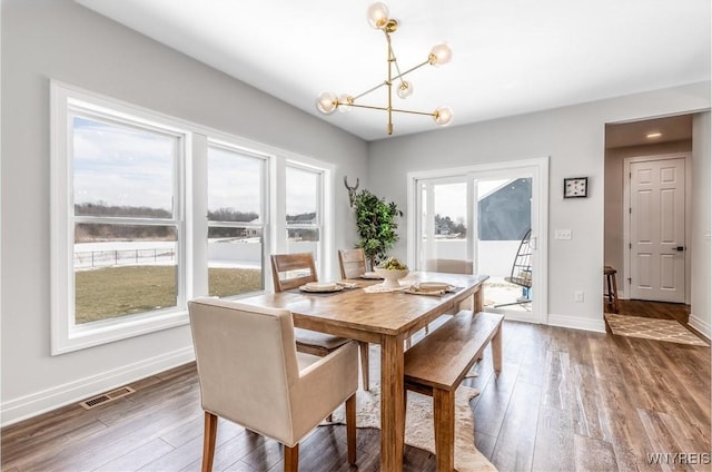 dining room with a chandelier, wood finished floors, visible vents, and baseboards