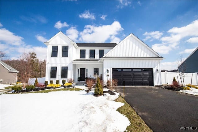 modern farmhouse style home featuring board and batten siding, fence, a garage, and aphalt driveway