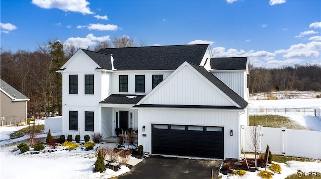 modern farmhouse style home with a garage, a gate, fence, and aphalt driveway