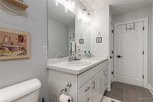 bathroom with double vanity, a sink, toilet, and tile patterned floors