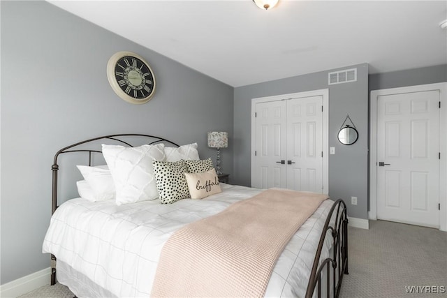 carpeted bedroom with a closet, visible vents, and baseboards