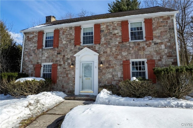 colonial house with stone siding and a chimney