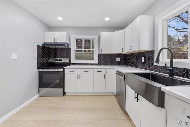 kitchen with decorative backsplash, appliances with stainless steel finishes, under cabinet range hood, white cabinetry, and a sink