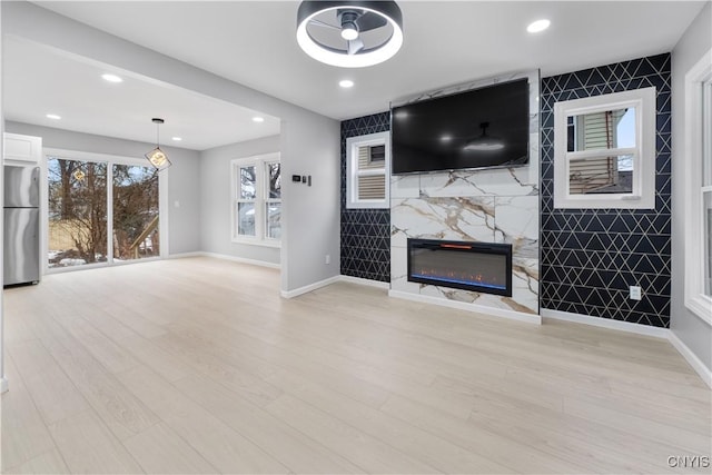 unfurnished living room with light wood-style floors, recessed lighting, a fireplace, and baseboards