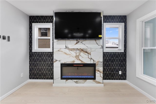 details with baseboards, wood finished floors, and a glass covered fireplace