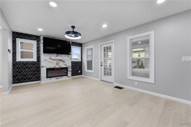 unfurnished living room featuring a fireplace, recessed lighting, visible vents, light wood-style flooring, and baseboards