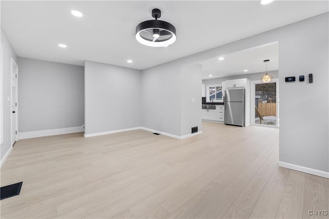 unfurnished living room with light wood-type flooring, visible vents, baseboards, and recessed lighting