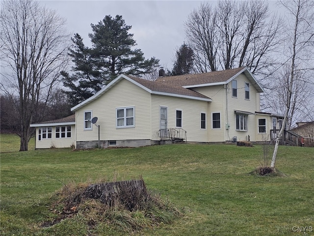 rear view of property featuring a shingled roof, a yard, and a chimney