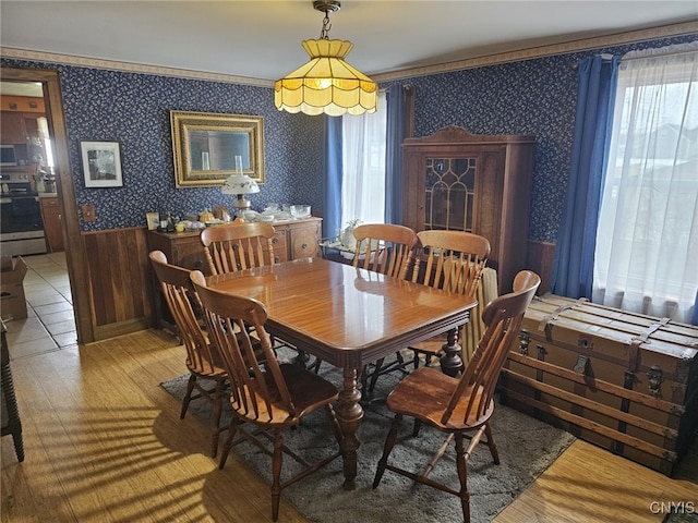 dining space featuring a wainscoted wall, crown molding, and wallpapered walls