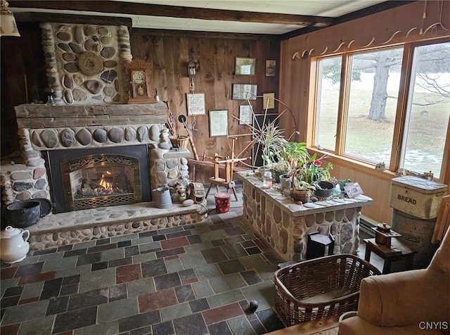 interior space featuring stone finish floor, a fireplace, beam ceiling, and wooden walls