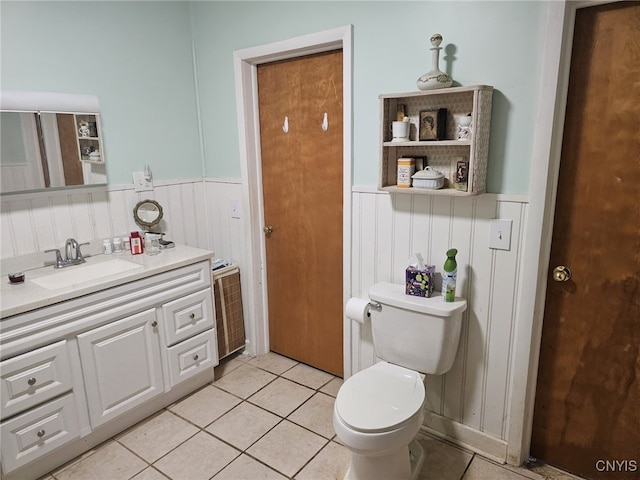 bathroom featuring vanity, wainscoting, tile patterned flooring, and toilet