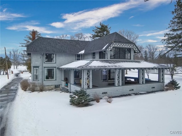 view of front of property featuring covered porch, a shingled roof, and a chimney