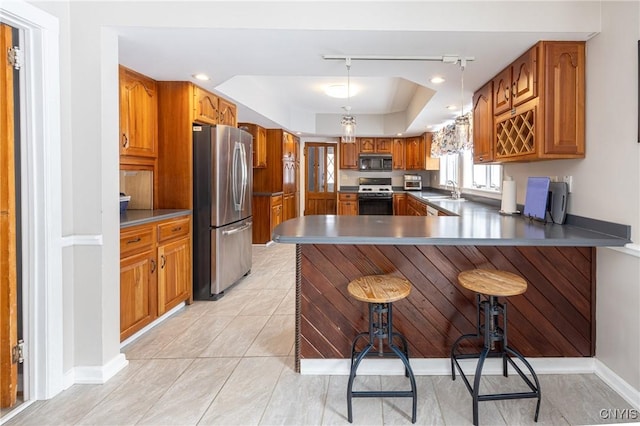 kitchen featuring range with gas cooktop, a raised ceiling, freestanding refrigerator, black microwave, and a peninsula