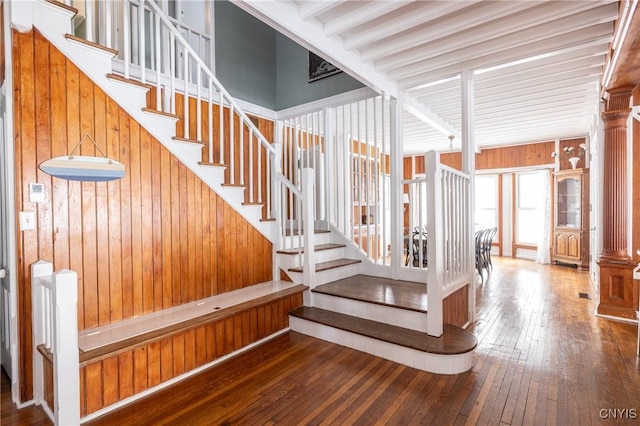 stairs with wood walls, decorative columns, and hardwood / wood-style flooring