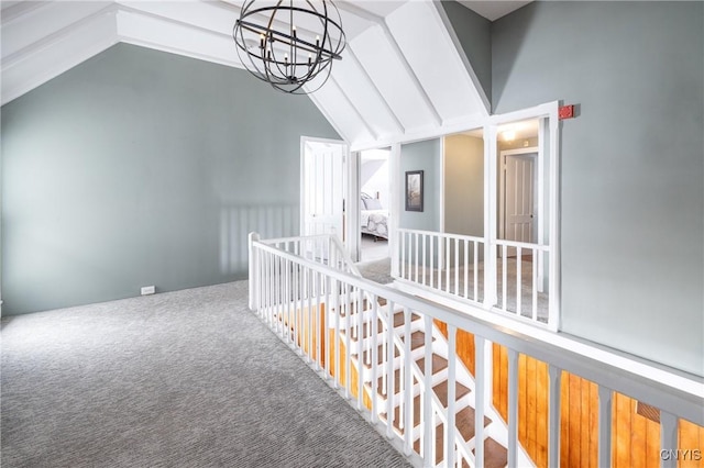 hallway featuring a chandelier, lofted ceiling, carpet, and an upstairs landing