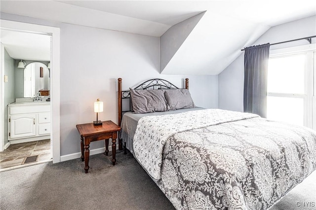 bedroom with lofted ceiling, connected bathroom, visible vents, baseboards, and carpet