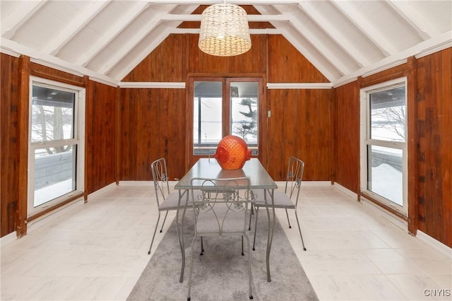 dining area featuring a healthy amount of sunlight, wooden walls, and a chandelier