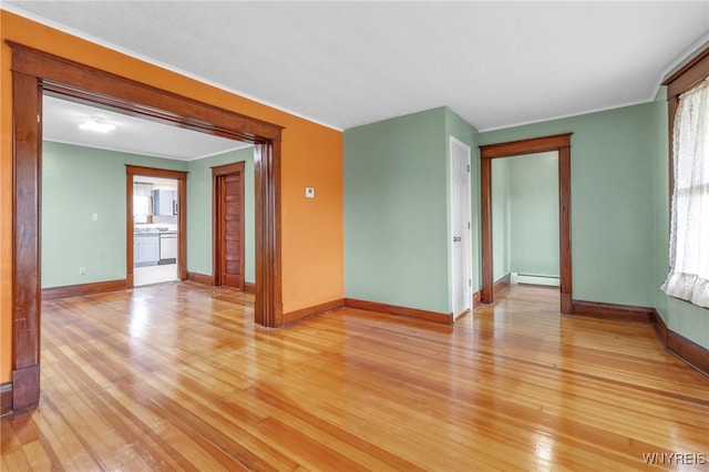 spare room with light wood-style floors, baseboards, crown molding, and baseboard heating