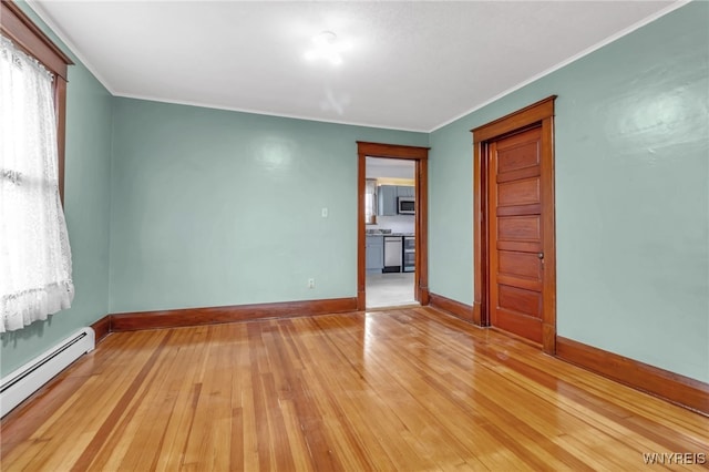 empty room with baseboards, light wood-style flooring, crown molding, a baseboard heating unit, and a wealth of natural light