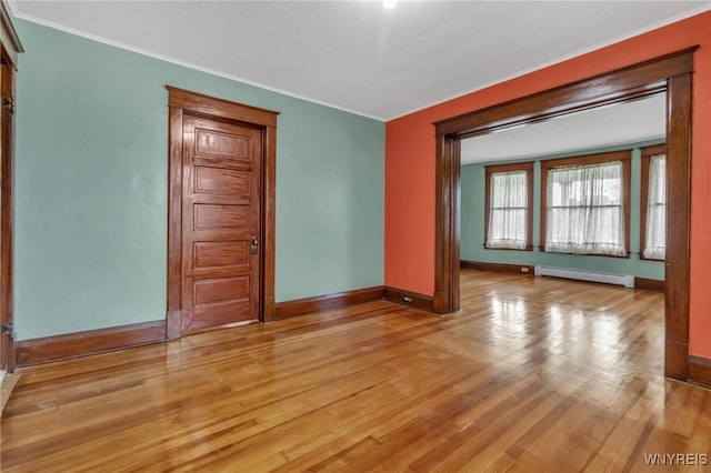 empty room with light wood finished floors, a baseboard radiator, baseboards, and ornamental molding