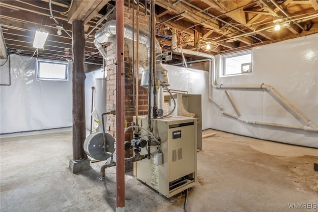 below grade area featuring gas water heater, plenty of natural light, and a heating unit