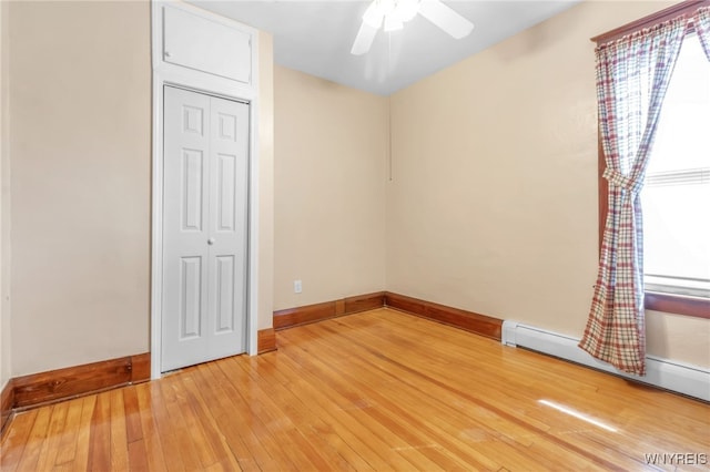 spare room with a ceiling fan, baseboard heating, baseboards, and light wood finished floors