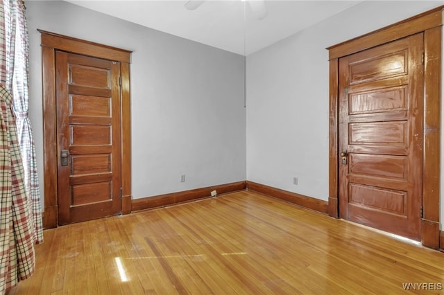 interior space featuring light wood-style floors, baseboards, and a ceiling fan