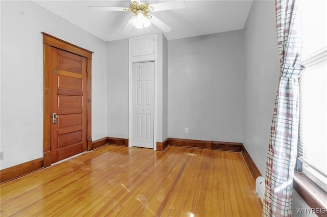 empty room featuring light wood-style floors, baseboards, and a ceiling fan