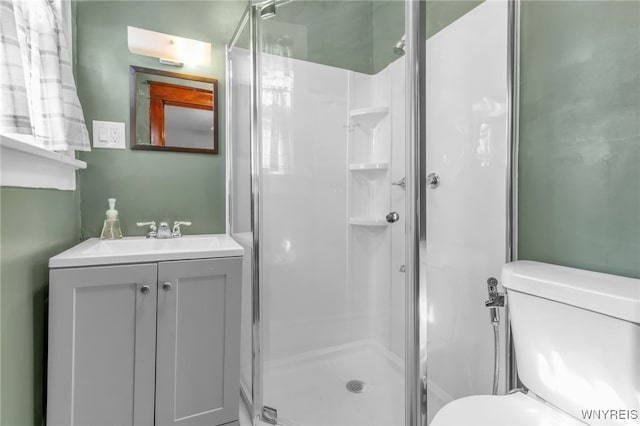 bathroom featuring vanity, a shower stall, and toilet