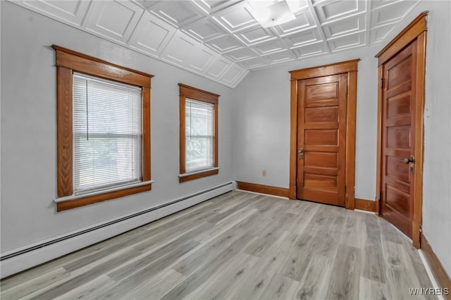 spare room with an ornate ceiling, a baseboard heating unit, light wood-style flooring, and baseboards