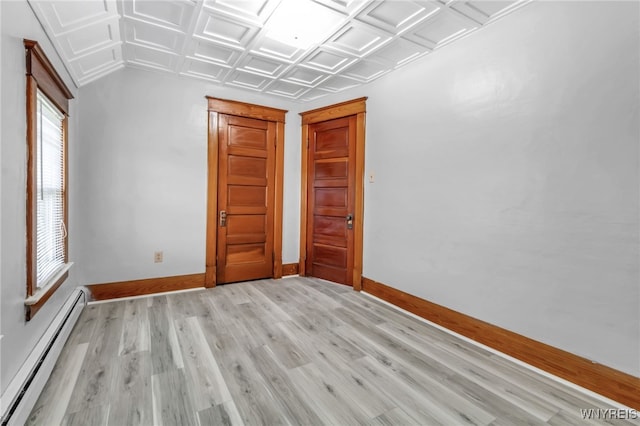 empty room with an ornate ceiling, baseboards, baseboard heating, and light wood-style flooring