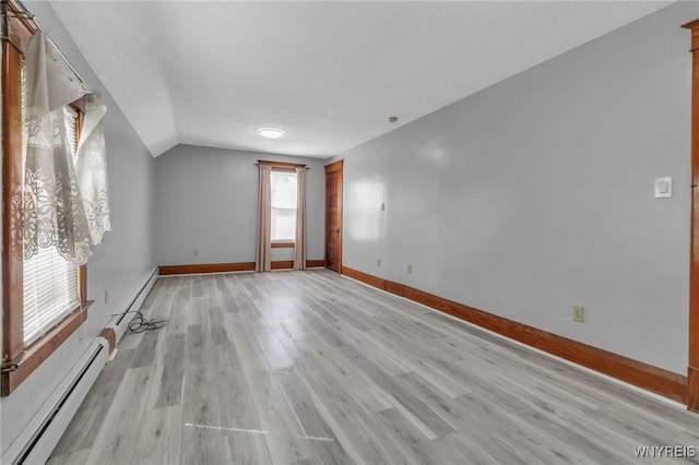 empty room with lofted ceiling, light wood-style flooring, a baseboard heating unit, and baseboards