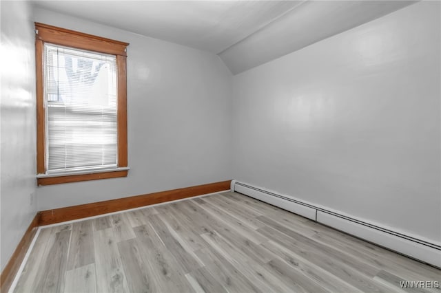 spare room featuring lofted ceiling, baseboards, a baseboard heating unit, and wood finished floors