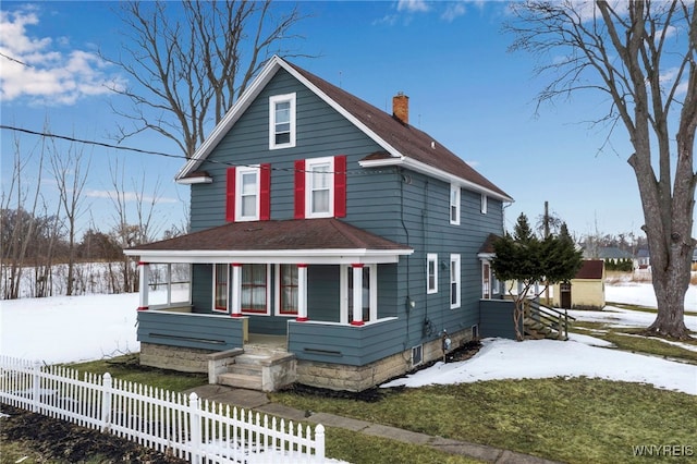 view of front of property with covered porch, a fenced front yard, a chimney, and roof with shingles