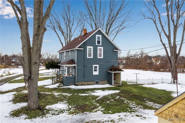 snow covered rear of property featuring fence and a chimney