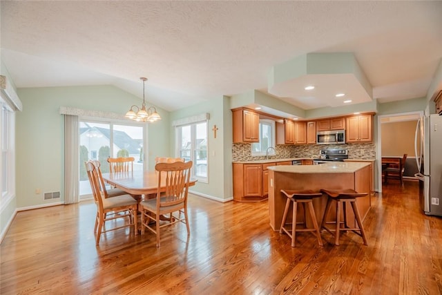 kitchen featuring stainless steel appliances, a kitchen island, visible vents, and decorative backsplash