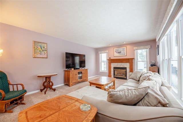 living area featuring baseboards, a fireplace, and light colored carpet