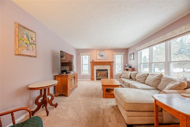 living area featuring baseboards, light carpet, a textured ceiling, and a tiled fireplace