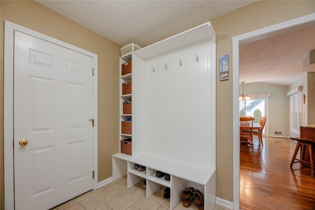 mudroom featuring a textured ceiling, light wood-type flooring, and baseboards