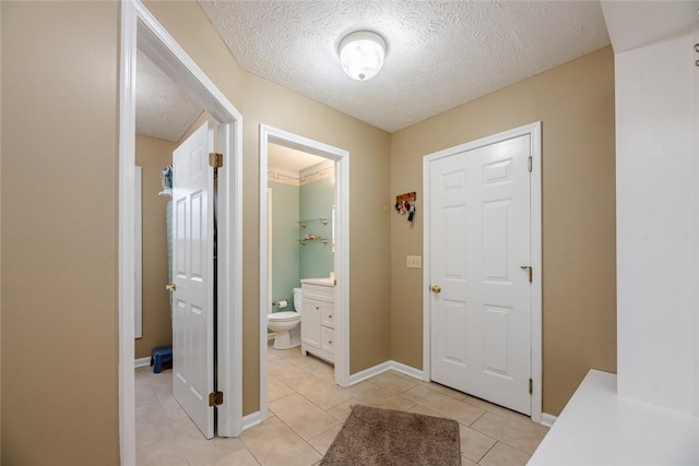 foyer entrance with light tile patterned floors, baseboards, and a textured ceiling